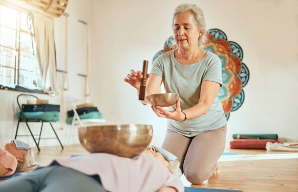 Meditation, tibetan bowl and zen senior women doing a sound healing or therapy practice in a studio